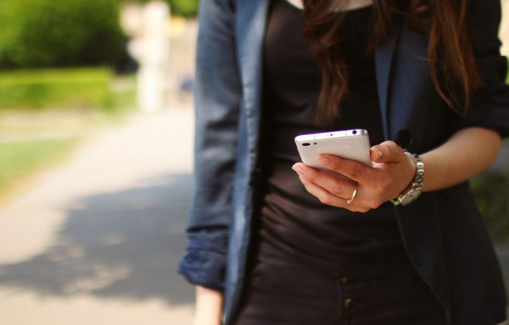 Imagem mostra mulher com celular na mão - frases para bio do Instagram