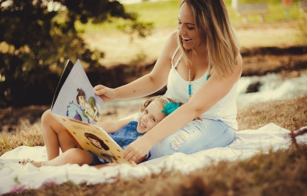 Imagem mostra mãe e filha lendo livro - frases para dia das mães