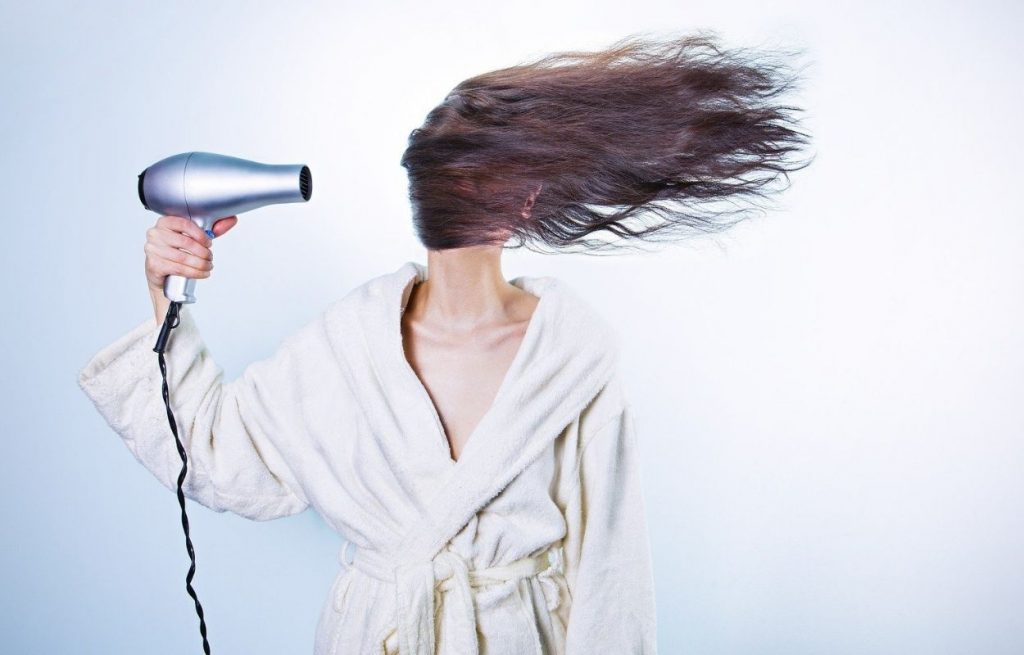 Imagem mostra mulher secando o cabelo - frizz