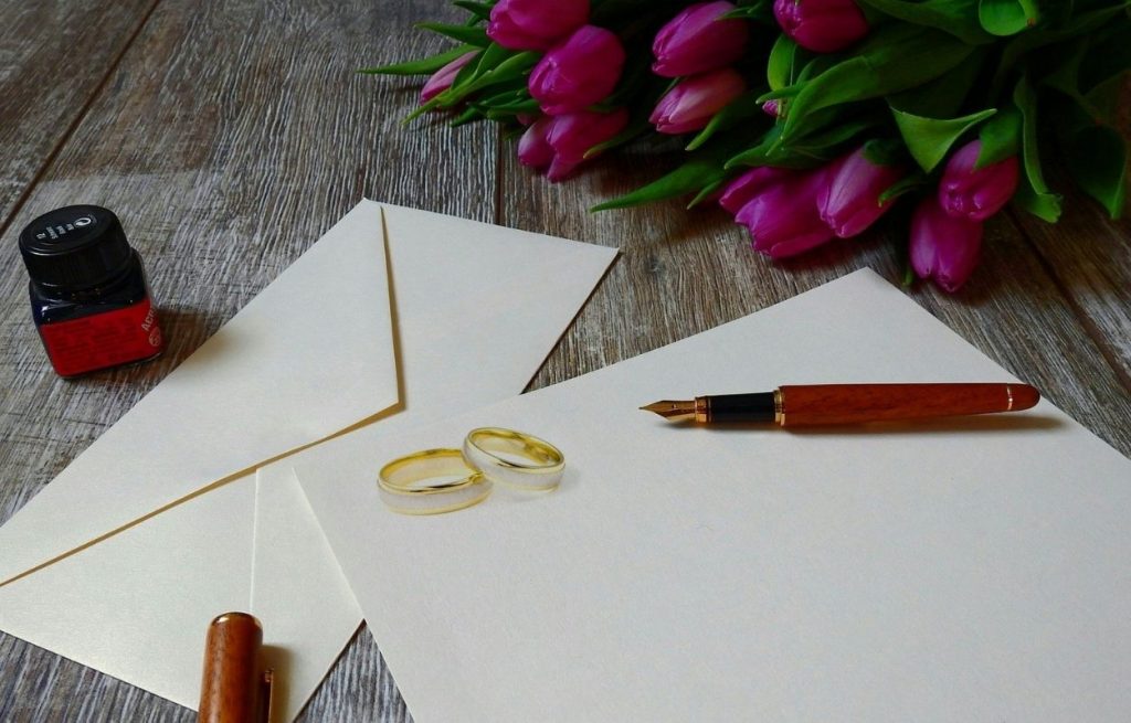 Imagem mostra envelope, canela e alianças - frases para convite de casamento