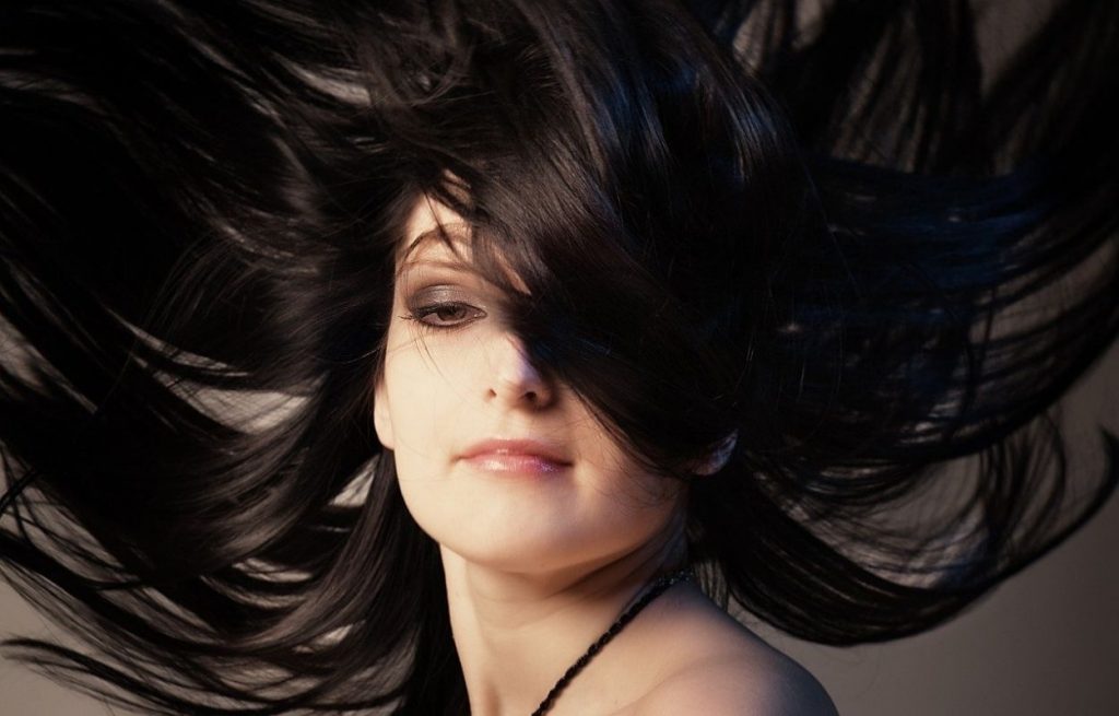 Imagem mostra mulher com cabelos pretos - henna para cabelo