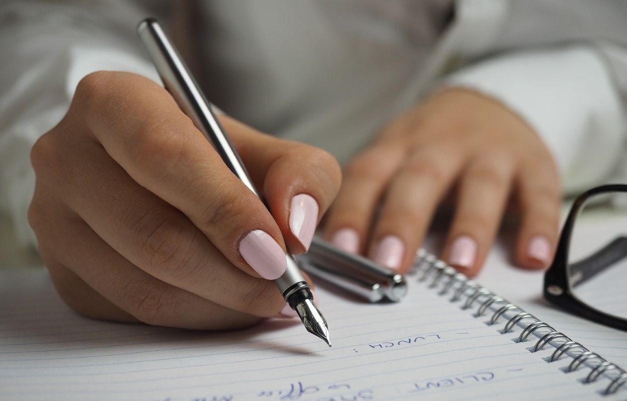Imagem mostra mulher anotando coisas em um caderno - como ser organizada