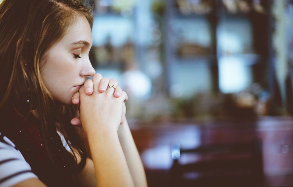 Imagem mostra mulher rezando - oração de cura
