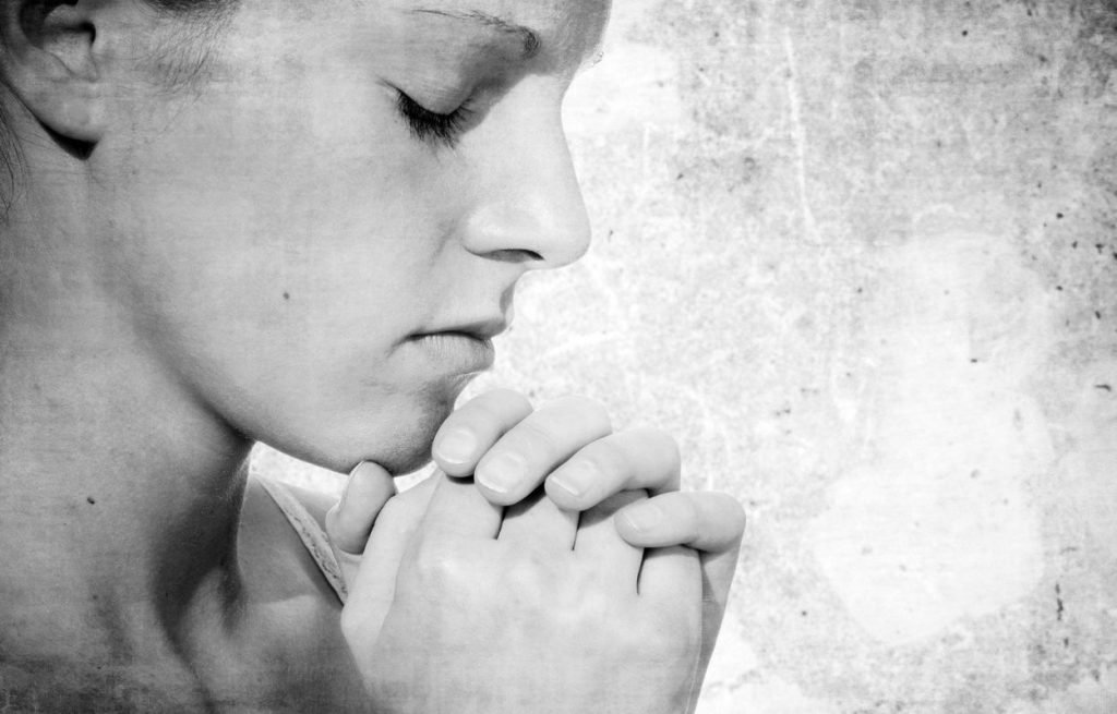 Imagem mostra mulher rezando - oração para ansiedade