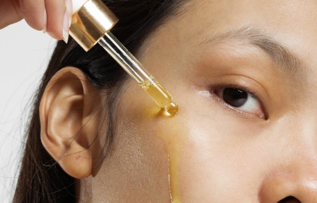Imagem mostra mulher aplicando óleo no rosto - cleansing oil