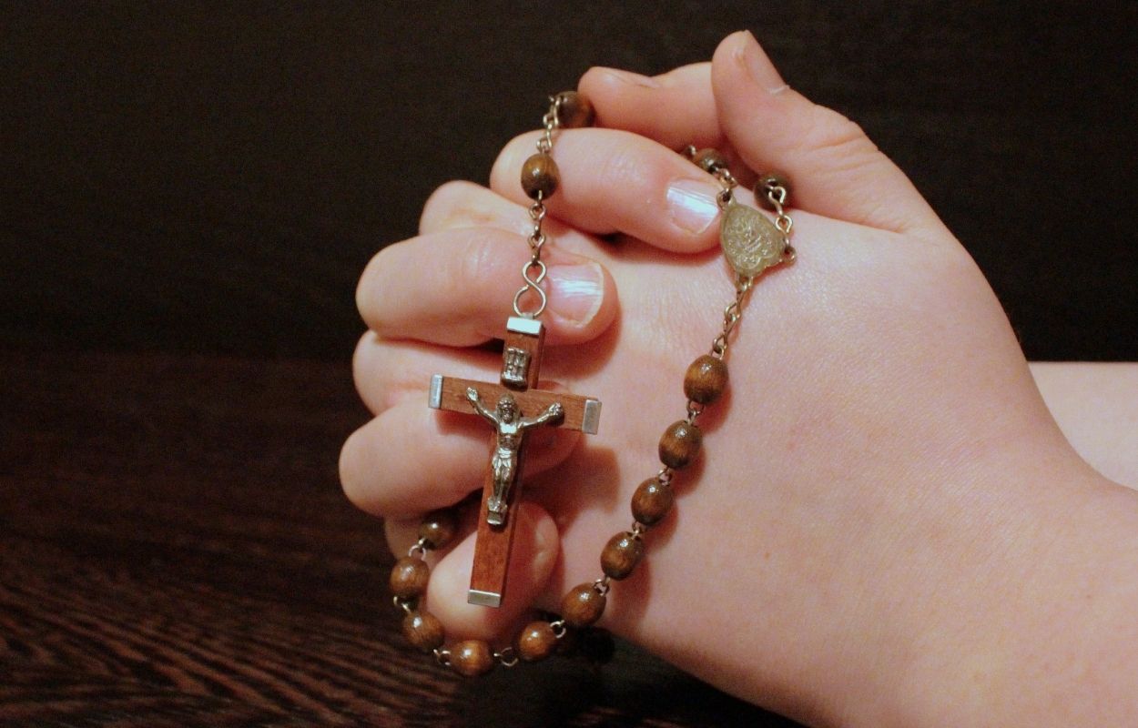 Imagem mostra mãos em prece com terço - oração do credo