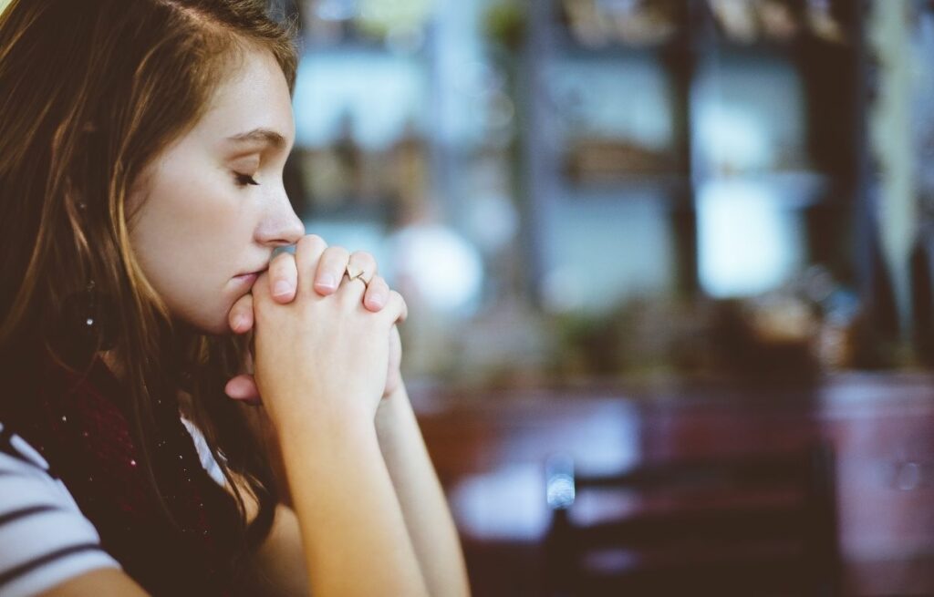Imagem mostra mulher rezando - oração do meio dia