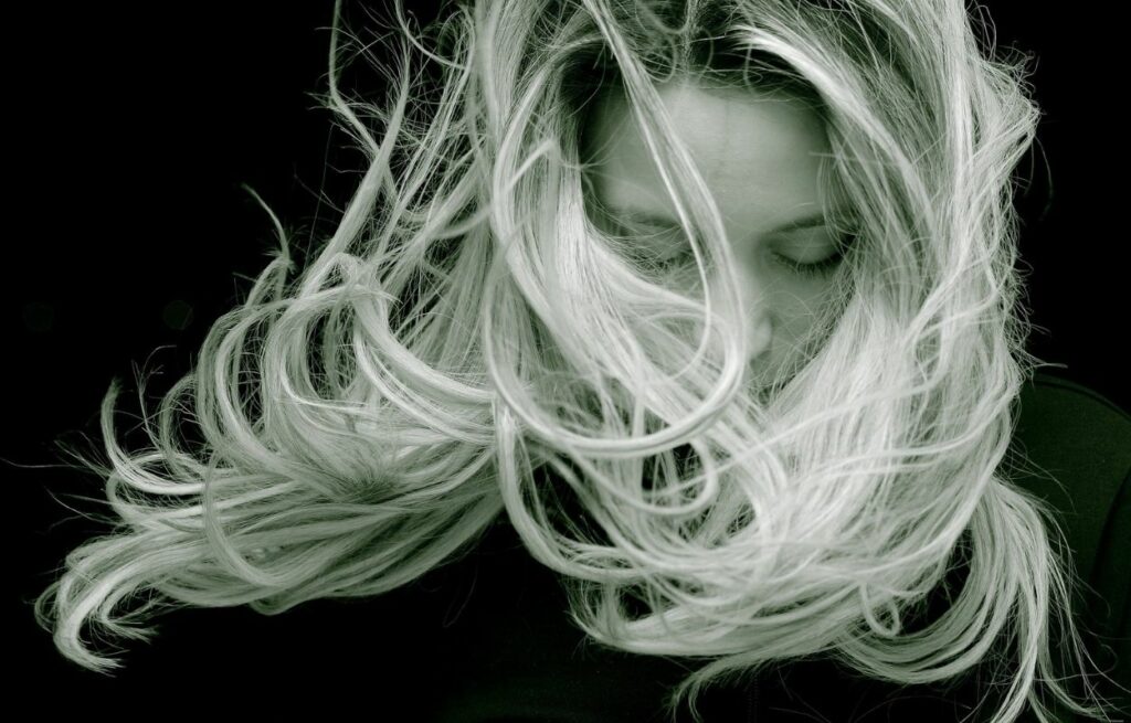 Imagem mostra mulher com cabelos em movimento - Como deixar o cabelo volumoso e grosso