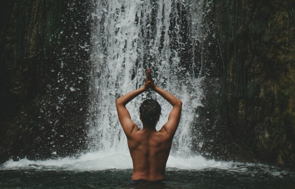 Imagem mostra mulher tomando banho de cachoeira - frases de cachoeira