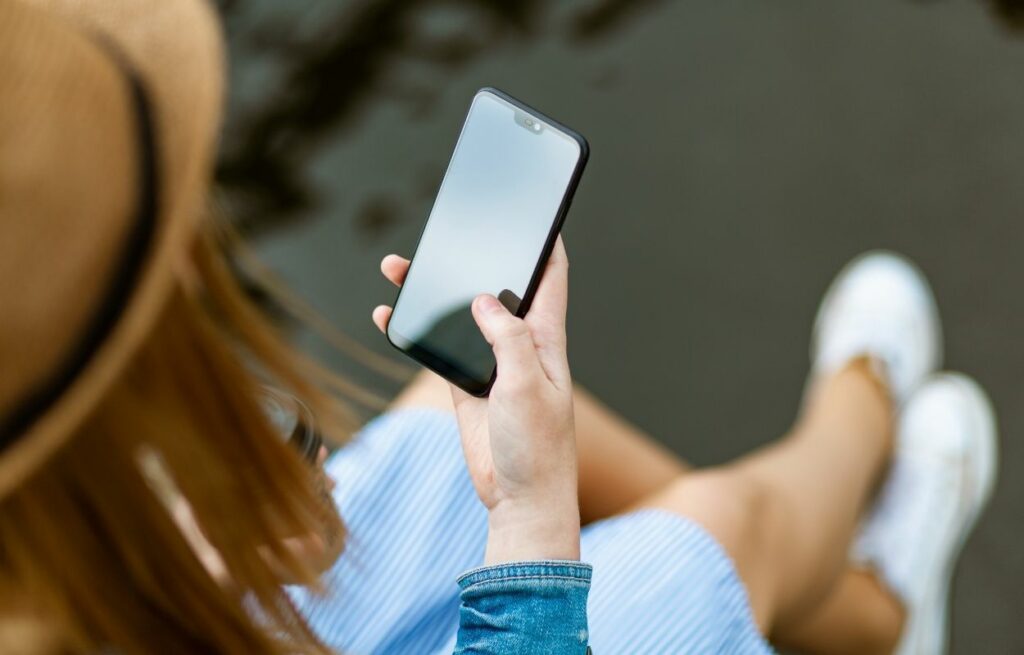 Imagem mostra mulher com celular na mão - frases de indireta para status