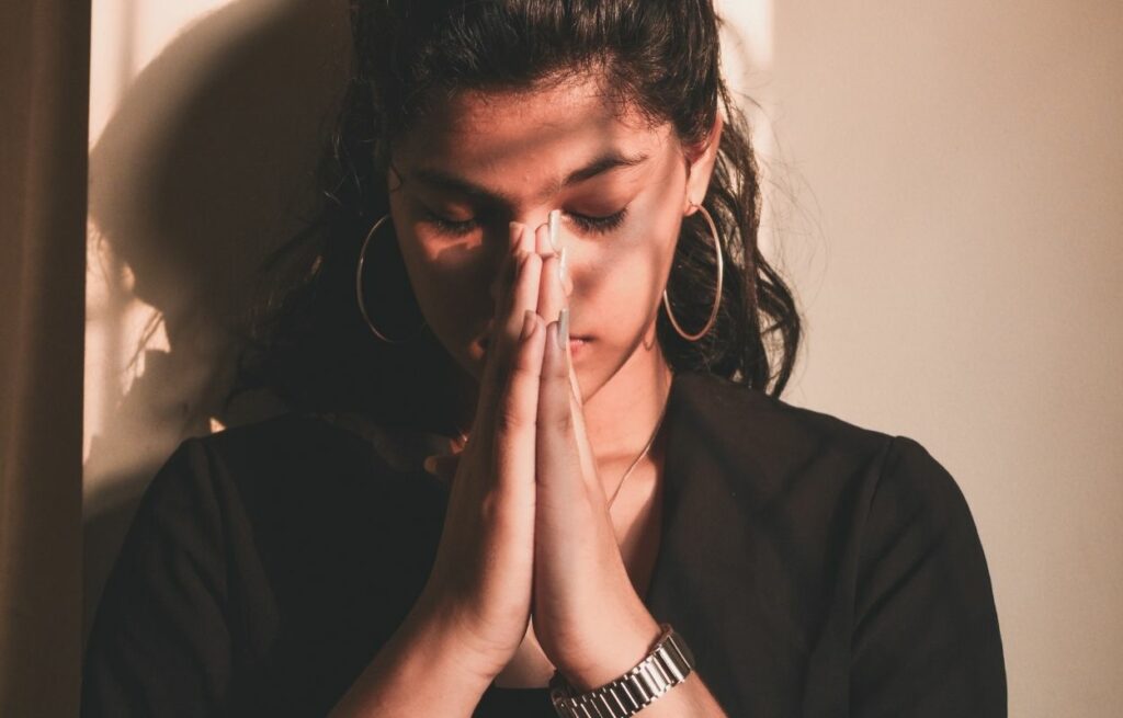Imagem mostra mulher orando - frases evangélicas para status