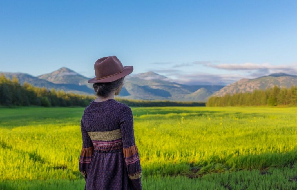 Imagem mostra mulher de chapéu no campo - legenda para foto no campo