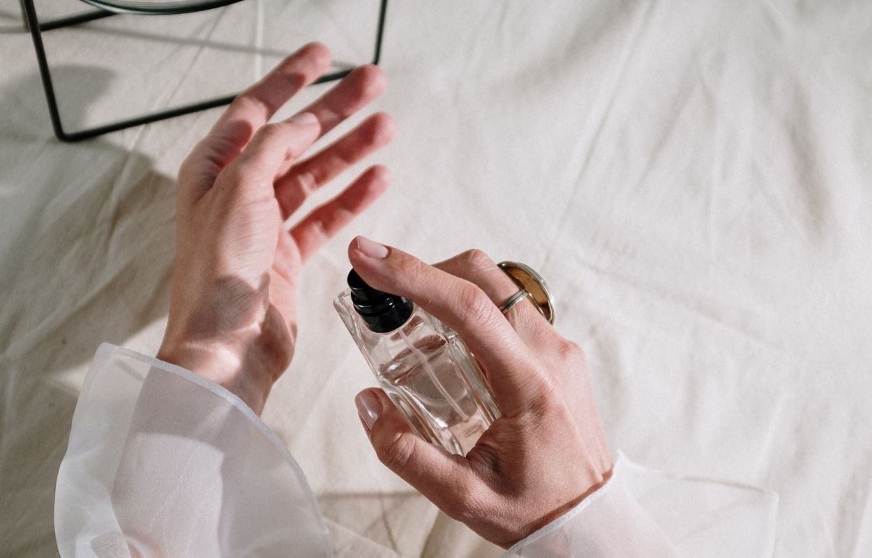 Imagem mostra pessoa aplicando perfume - simpatia da canela para o amor